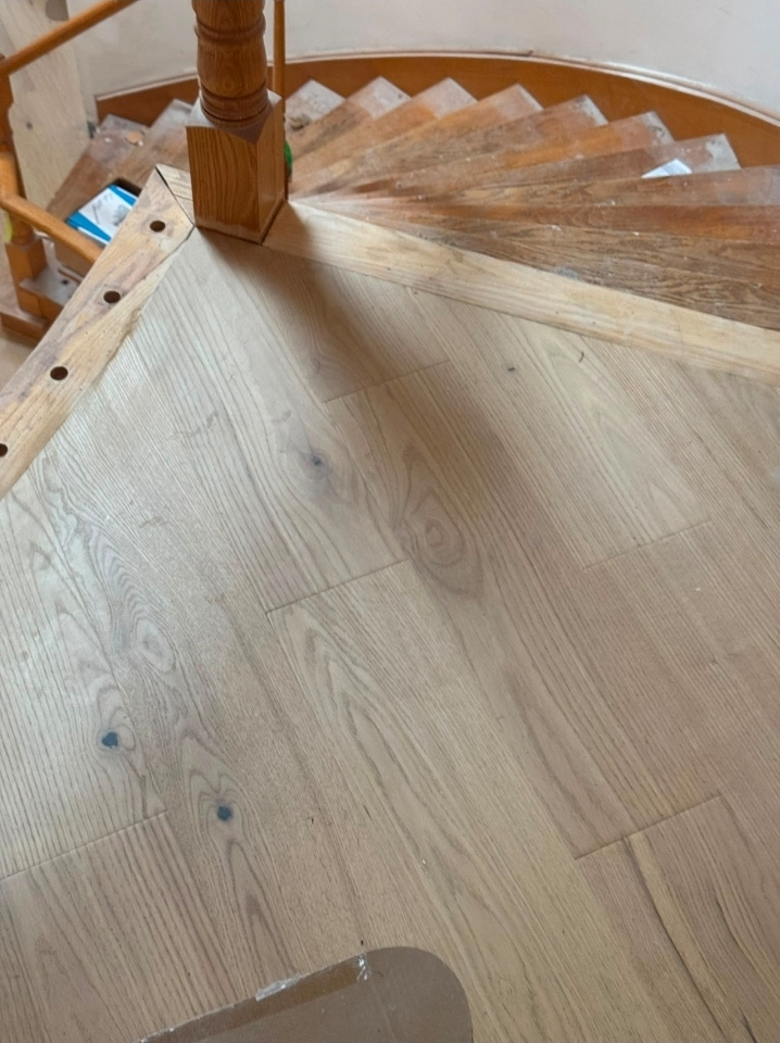 Hardwood flooring installation around a curved staircase in a Hamilton Ontario home