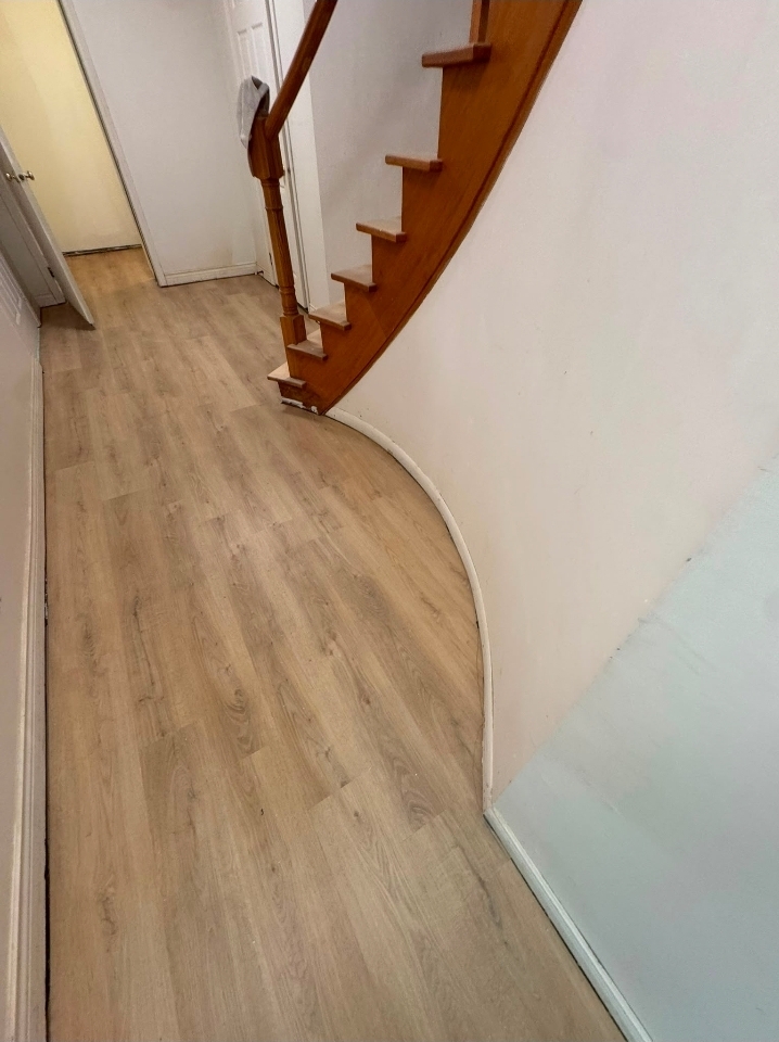 Vinyl plank flooring installed around a curved staircase wall in Hamilton